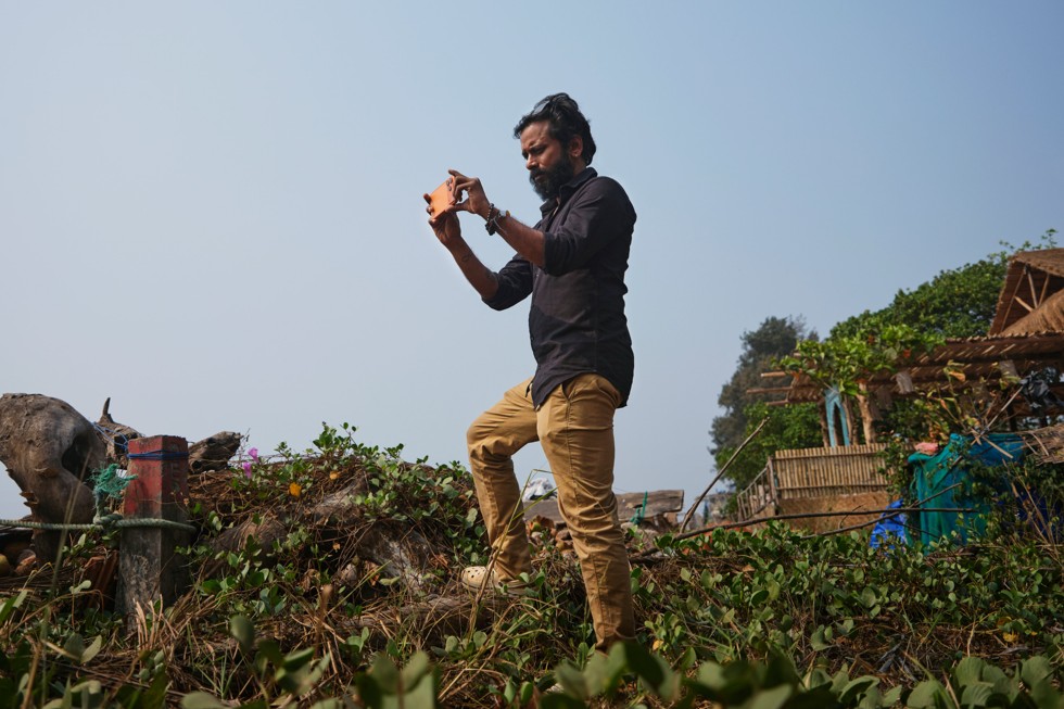 Ritesh Sharma filme avec un iPhone 17 Pro Max sur une colline herbeuse
